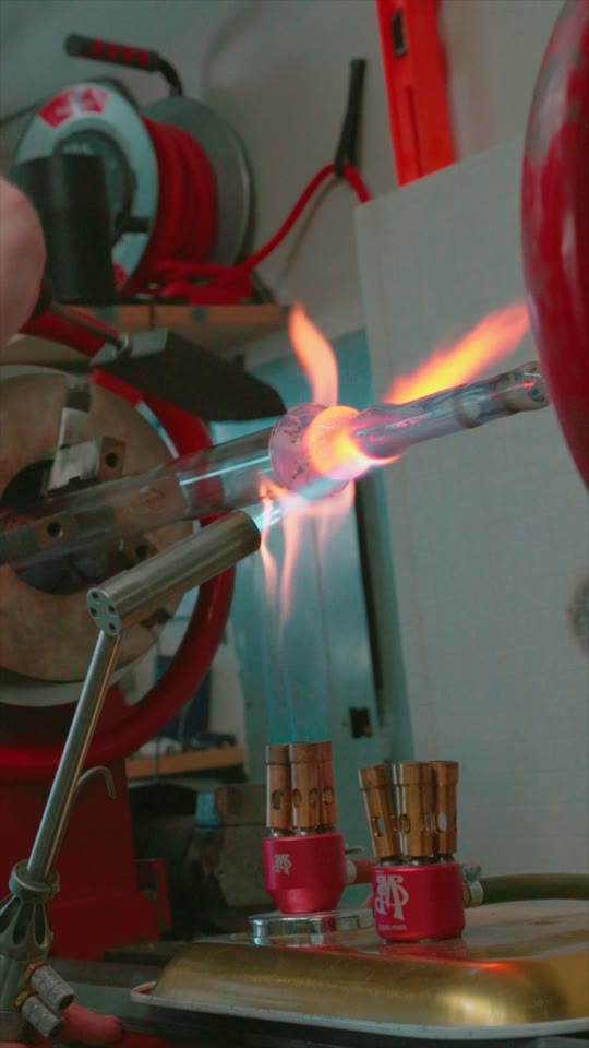 Glass artist working molten glass at a torch